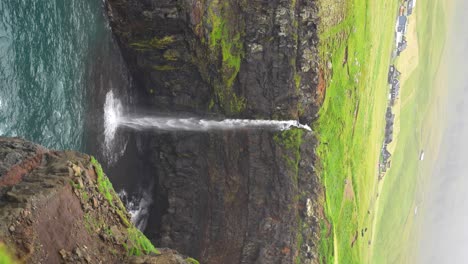 mulafossur waterfall cascading into the atlantic ocean near foggy gasadalur in faroe islands