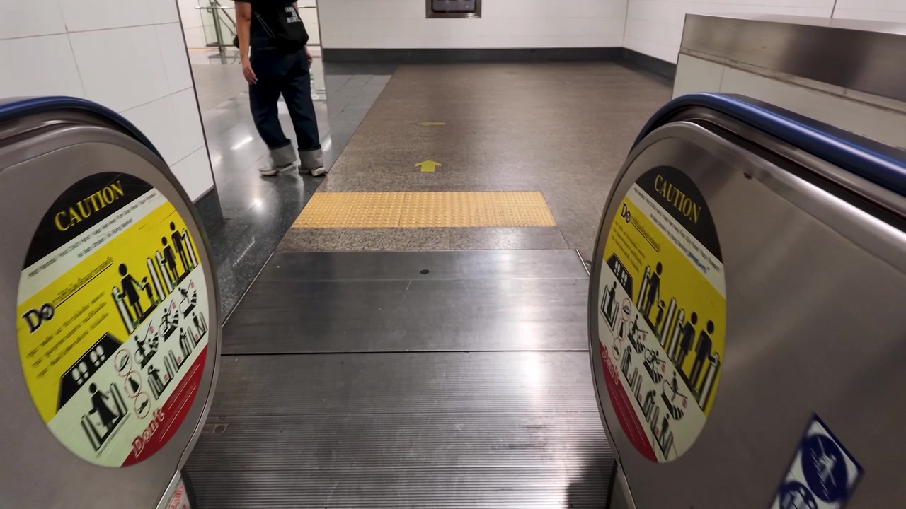 En person går bort fra en metallrulletrapp på en moderne T-banestasjon i Bangkok.