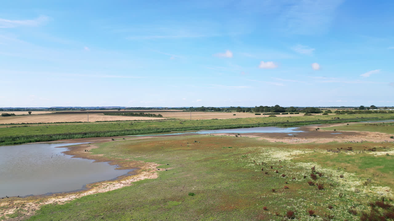 위에서, 비디오 영상은 링컨셔 해안의 매혹적인 소금물 습지를 보여줍니다. 비행하는 바다새와 호수와 내륙 호수에서