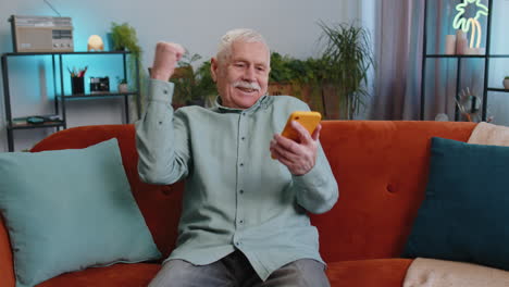 Grandfather-old-man-at-home-use-smartphone-typing-browsing-wow-yes-found-out-great-big-win-celebrate