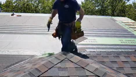a skilled worker carefully installs shingles on a residential roof, demonstrating expertise and precision.