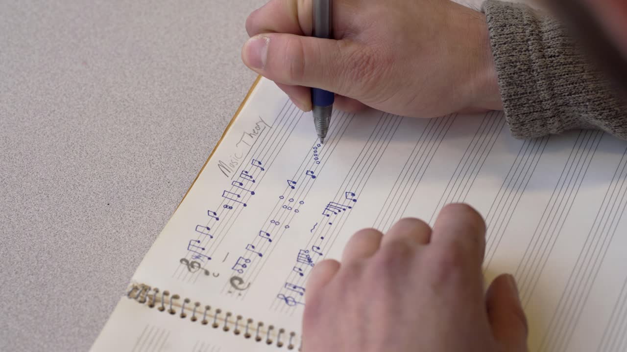 A Man Drafting Musical Notes In His Music Notebook - Close Up Shot