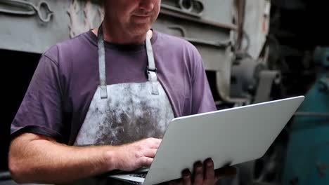 blacksmith using laptop in workshop 4k