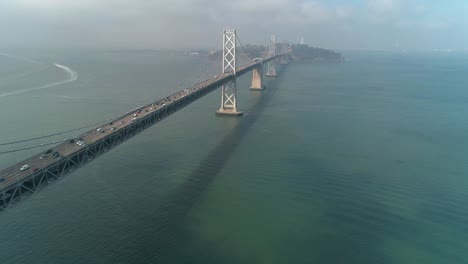 Luftaufnahme-Von-Fahrzeugen,-Die-Sich-Auf-Der-San-Francisco-oakland-Bay-Bridge-Mit-Der-Stadt-Im-Hintergrund-Bewegen