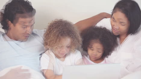 family with laptop on their bed