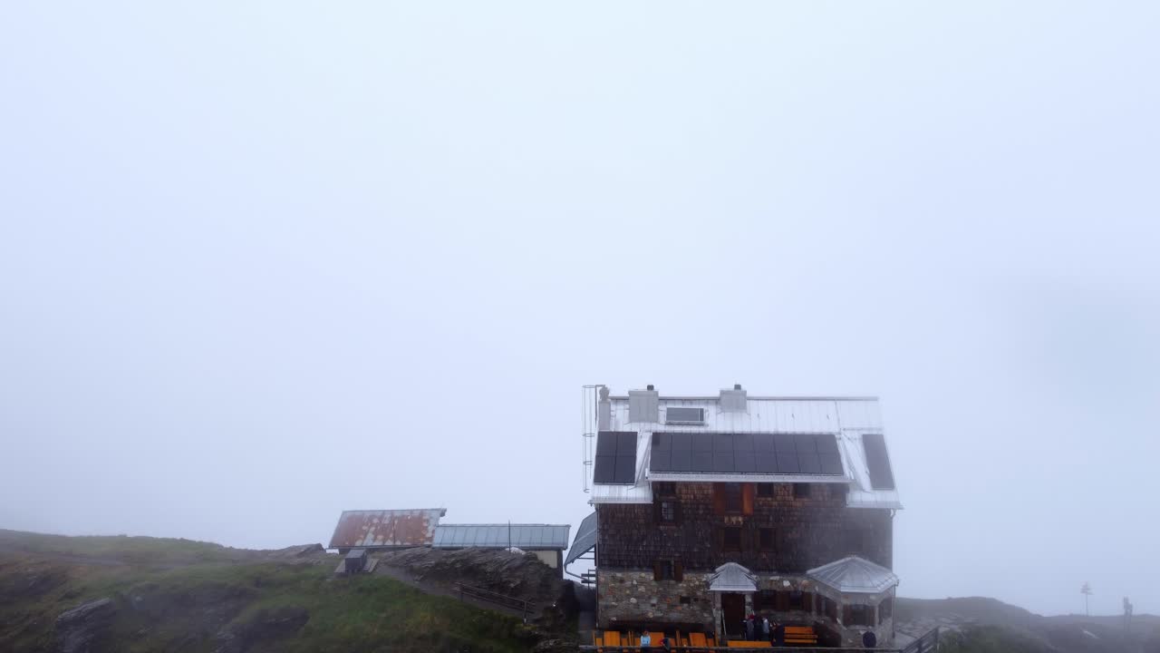 Et hus på en bjergryg på en meget tåget dag i Alperne