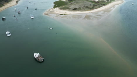 Aerial-view-of-fishing-boats-anchored-across-peaceful-ocean-waters-of-Chatham-Pier,-Cape-Cod