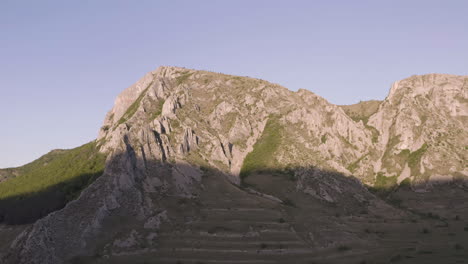 Early-morning-sunlight-illuminates-top-half-of-Piatra-Secuiului,-Romania,-near-villages-of-near-villages-of-Rimetea-and-Pietroasa