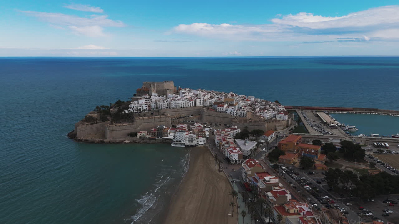 Evening aerial orbit of Peniscola castle surrounded by soft golden light and sea waves