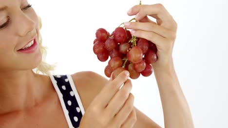 beautiful woman looking at bunch of red grapes