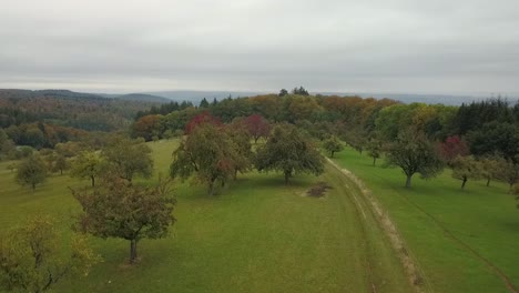 Ascending-over-beautiful-mountainous-area-with-dirt-road-during-foogy-fall-season,-Germany