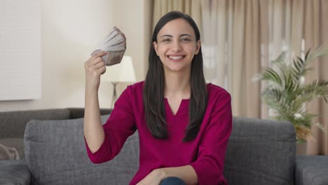 happy indian woman using money as fan