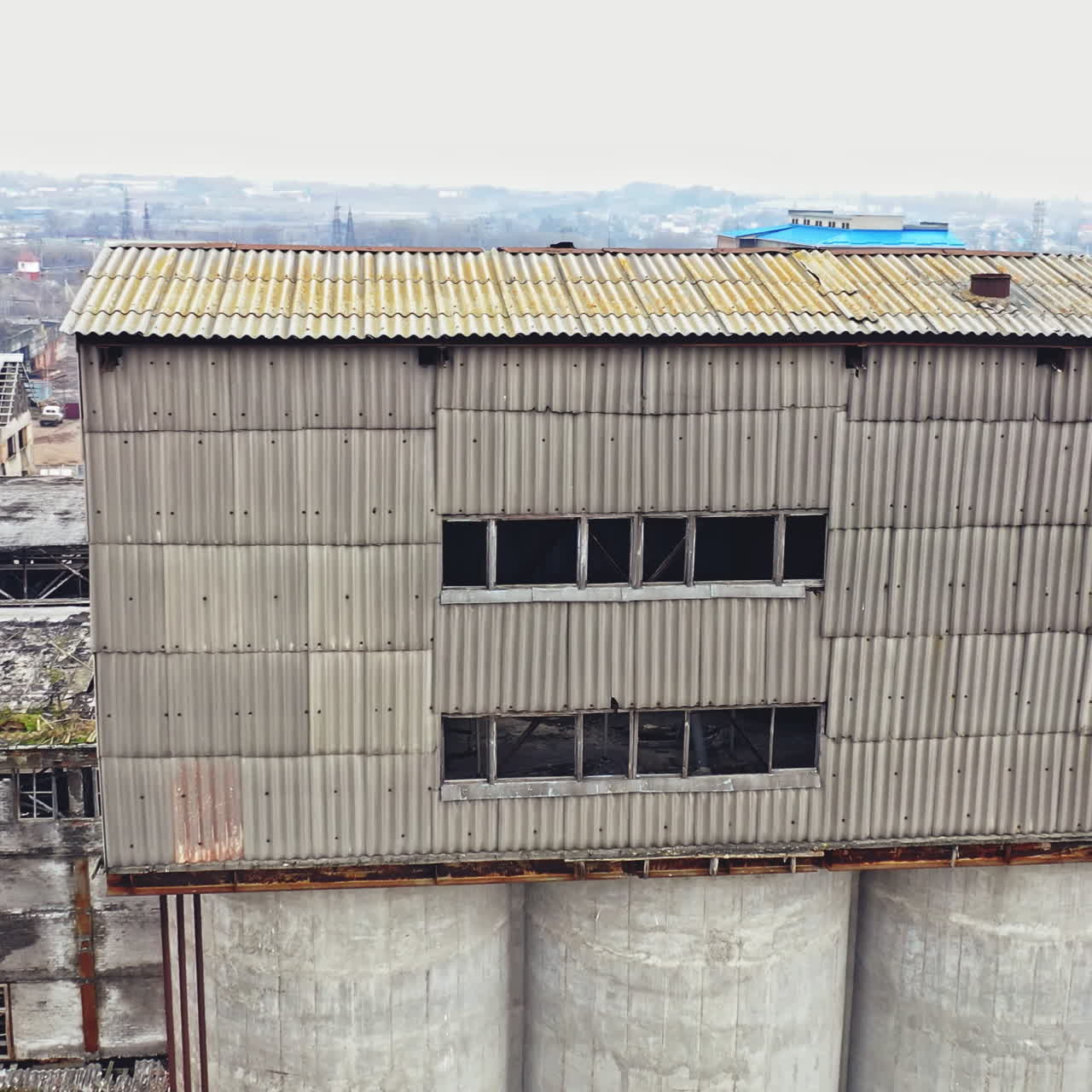 Flight over the empty old plant almost ruined in the city after the war. Old abandoned buildings without windows are broken-down. Camera moves around