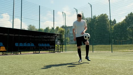 a young soccer man training freestyle tricks with the ball on a street football pitch on a sunny day 8