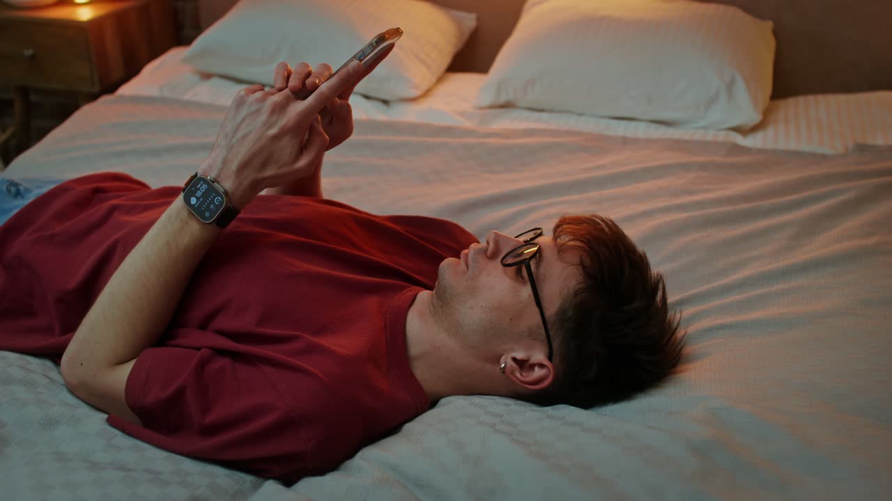밤에 침대에서 스마트폰을 사용하는 남자