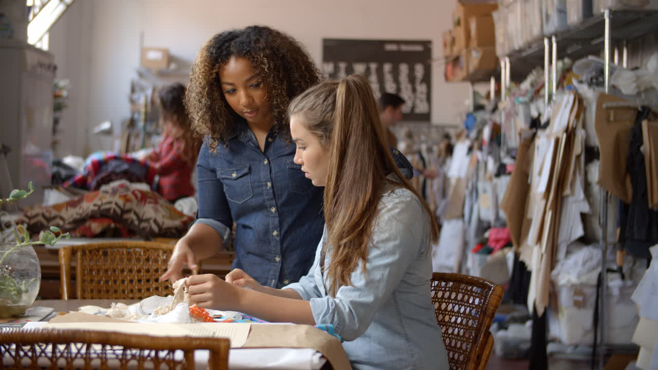 mujer se para para entrenar a un aprendiz en el estudio de diseño de ropa
