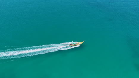 vista aérea de un barco de cola larga que navega a través de las aguas turquesas en phuket, tailandia, bajo la luz del día brillante con una atmósfera serena