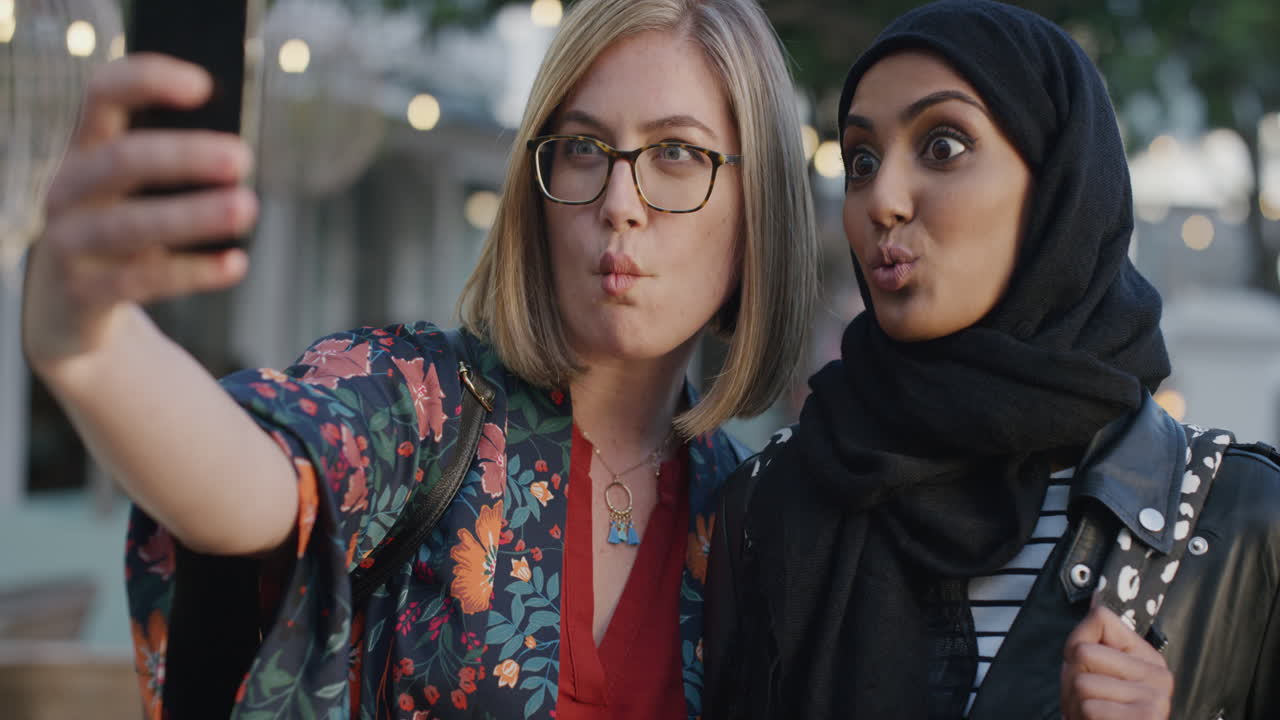 retrato de mujeres jóvenes felices amigos tomando fotos selfie usando teléfonos inteligentes haciendo caras disfrutando de las vacaciones pasar el rato con chicas multiétnicas divirtiéndose en el teléfono móvil en la ciudad