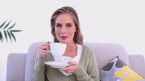 content woman drinking from cup sitting on couch