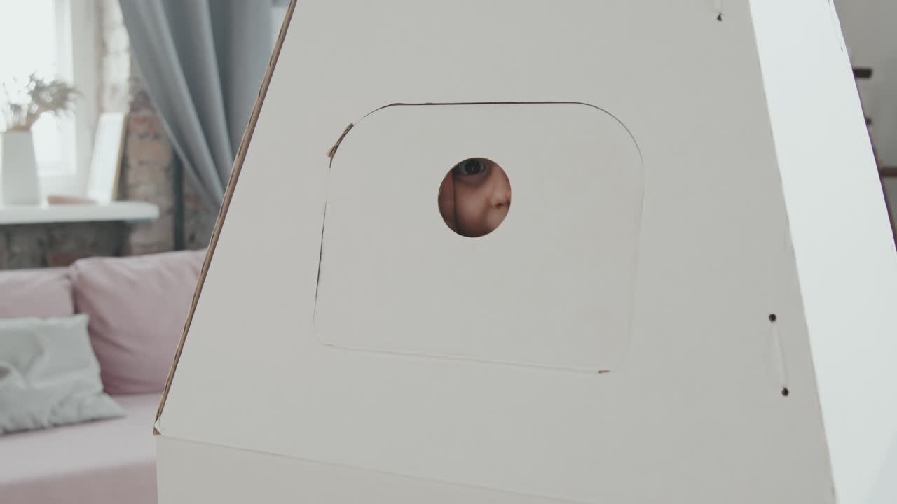 Cute Girl Hiding in Cardboard Rocket Ship Toy