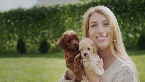 portrait of a pregnant woman with puppies in her hands, standing in the backyard of the house