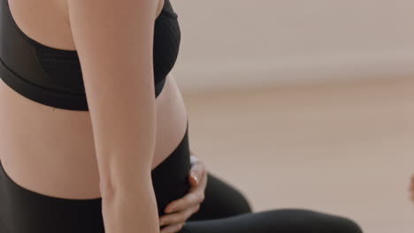 Retrato-De-Clase-De-Yoga-Hermosa-Mujer-Embarazada-Sentada-En-Una-Colchoneta-De-Ejercicios-Disfrutando-De-Un-Estilo-De-Vida-Saludable-Relajándose-En-El-Gimnasio-Tocando-El-Vientre