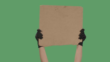 manos con guantes negros recoger un cartel en blanco de una caja de cartón. espacio en blanco para su eslogan, logotipo o anuncio. concepto de diseño de banner. aislado una pantalla verde, clave de croma. cerrar. cámara lenta