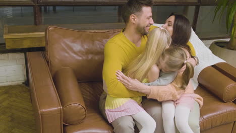 dolly zoom of a happy family hugging and spending time together while sitting on sofa at home