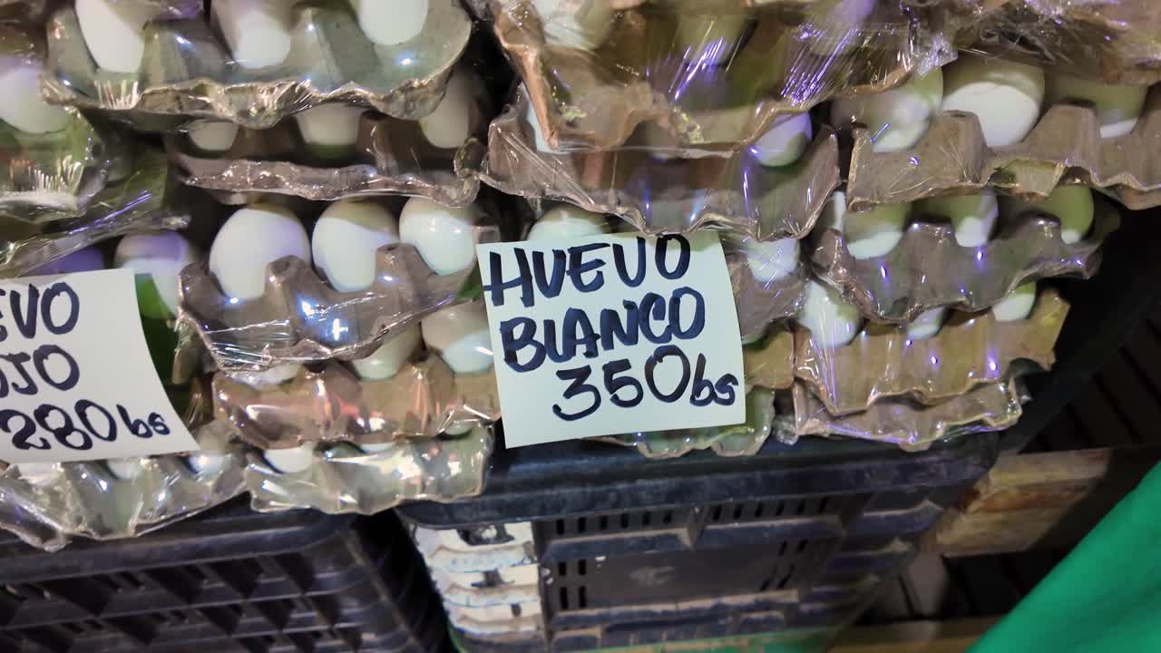 Stacks of white eggs with handwritten price tags at a local market stall, economy Venezuela