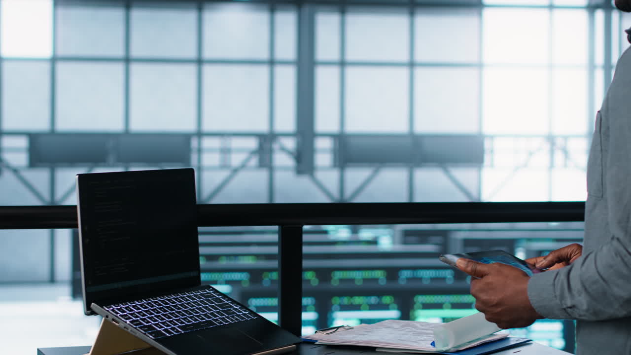 Technician in data center with laptop and tablet integrating AI technology