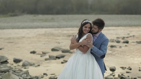 Wedding-couple-standing-near-mountain-river.-Groom-and-bride-in-love