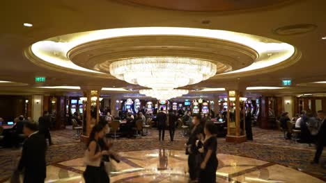 a bustling casino scene illuminated by glamorous chandeliers, showcasing gamblers engaged at slot machines and tables in a lively, opulent atmosphere