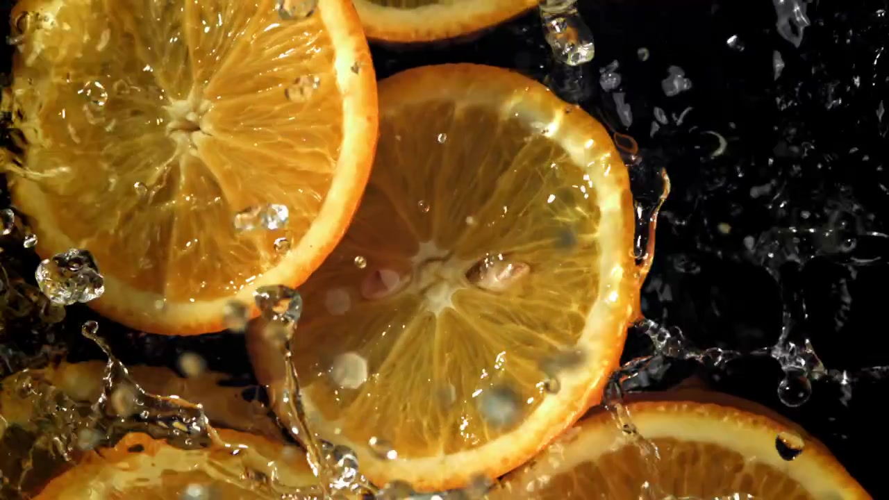 Fette d'arancia vivaci che si tuffano in acqua limpida