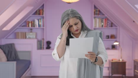 una anciana india estresada leyendo informes.
