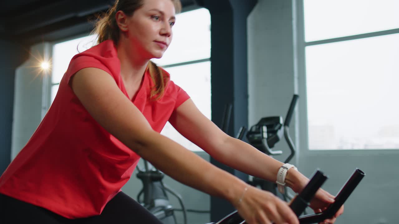 Woman performs aerobic endurance training workout cardio routine on the simulators cycle training