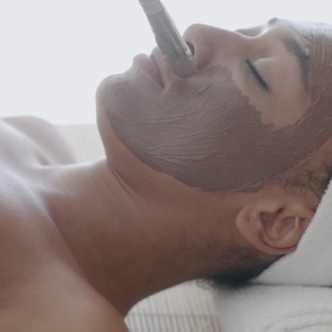 woman with clay facial mask in spa