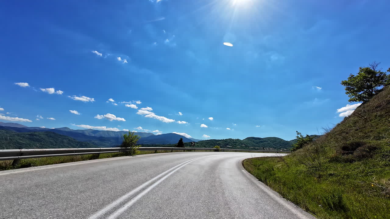 Winding mountain road with a car under a bright sunny sky