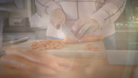 animación de puntos parpadeantes de luz sobre la mujer cortando zanahorias en la cocina en casa