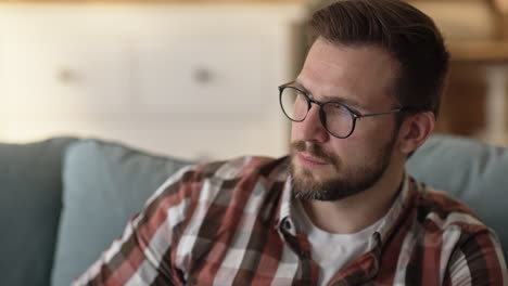 Man with glasses and plaid shirt sitting on couch