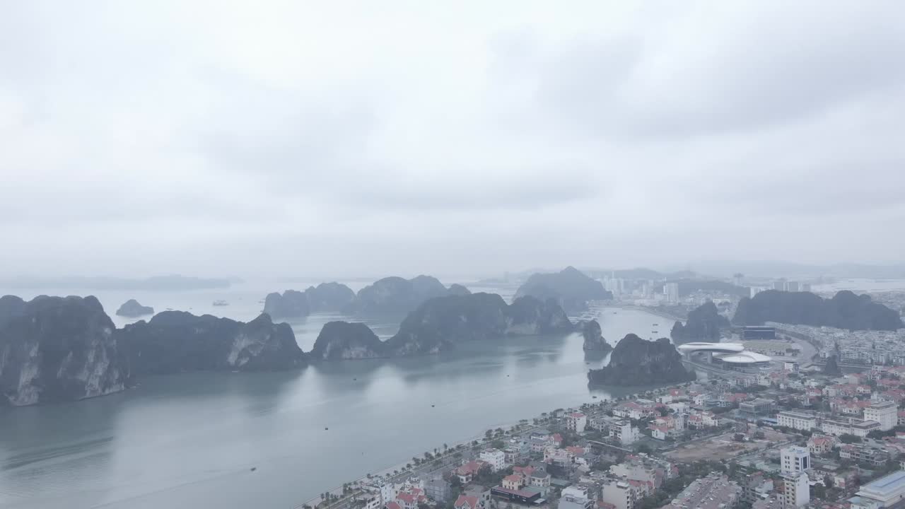 A sweeping aerial view of Hạ Long City, where dense urban landscapes meet the dramatic limestone karsts of Hạ Long Bay. This scene captures Northern Vietnam’s unique harmony of city of wonder