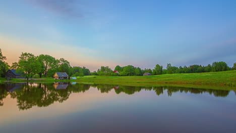 Timelapse-of-a-sunset-over-a-lake-and-rural-countryside-with-houses-and-barns-in-the-background