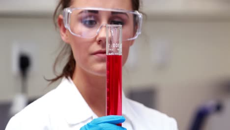 Scientist-looking-at-beaker-of-chemical