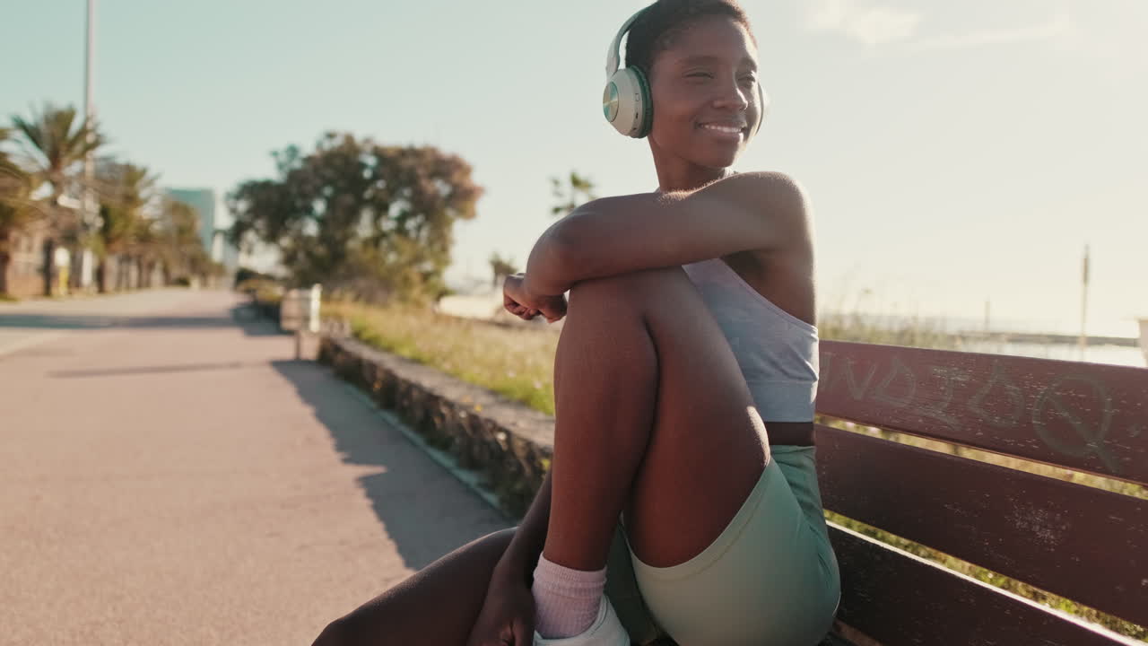 Smiling African American Woman with Headphones Relaxing on Bench Outdoors