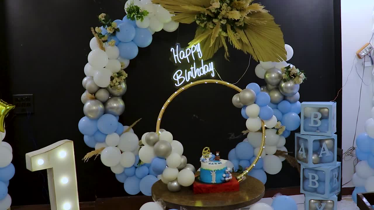 decoración de cumpleaños de un año con globos blancos y azules desde diferentes ángulos