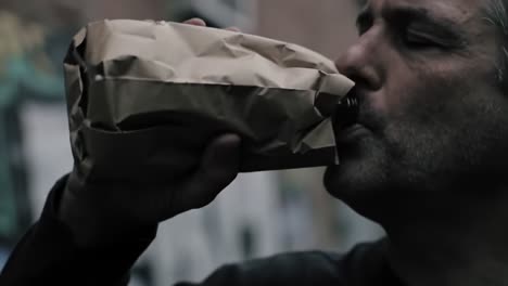 a contemplative moment captured in urban settings, depicting a man engaging with a wrapped beverage while reflecting on life amidst graffiti art