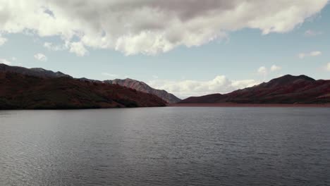 Low-flying-aerial-drone-shot-of-a-lake-and-mountain-ranges-in-Salt-Lake-City-with-fall-colored-leaves-at-60fps