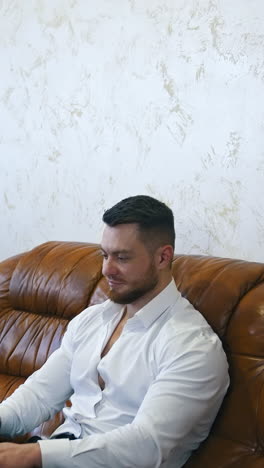 Handsome young businessman works on laptop in a hotel room. Man isresting after businessmeeting and surfing internet. Vertical video