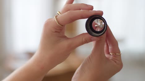 a diamond wedding ring getting looked at through a monocle with a woman's hands and nice bokeh background