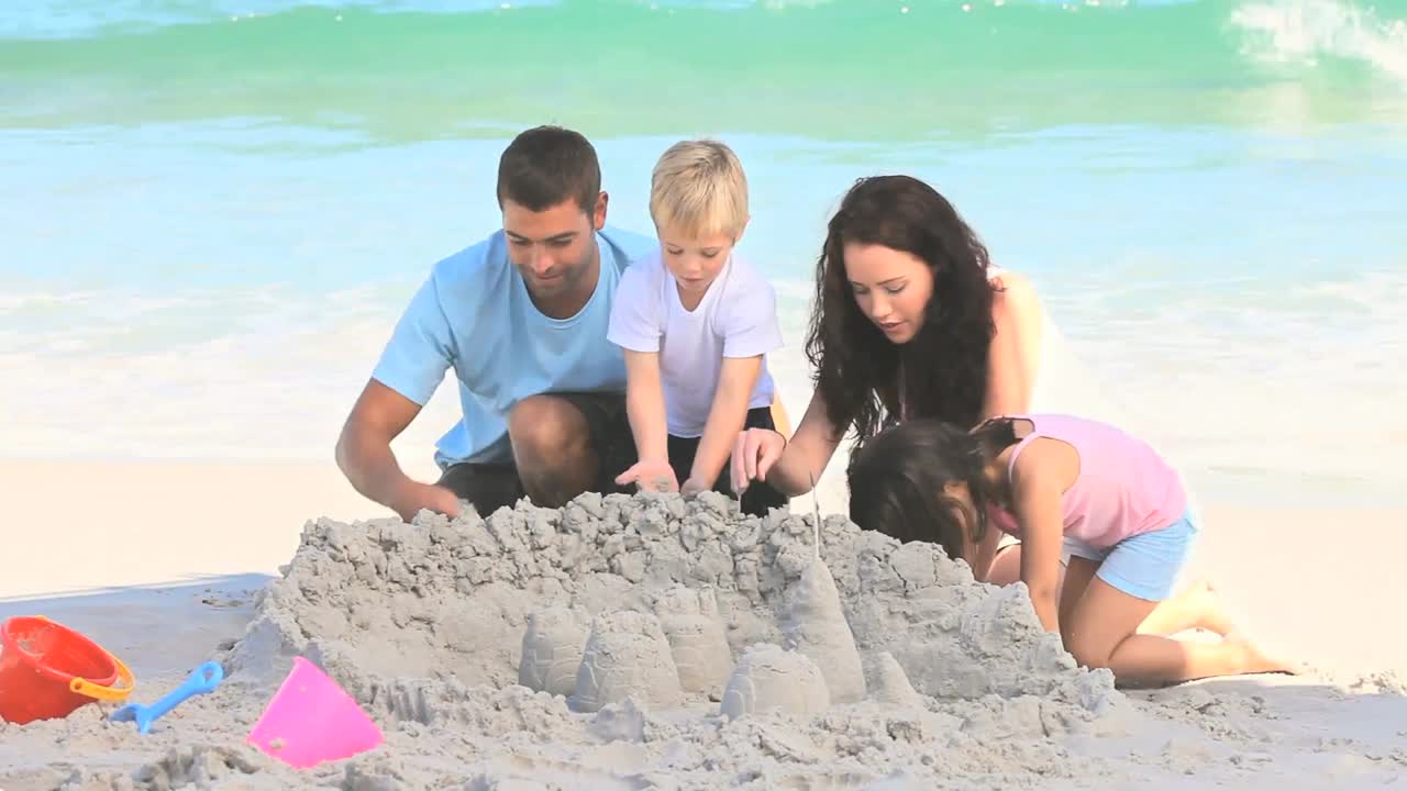 행복한 가족이 모래 성을 짓고 있습니다.