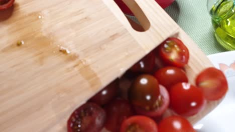 mujer pasando tomates cortados a la bandeja de ensalada con cuchillo